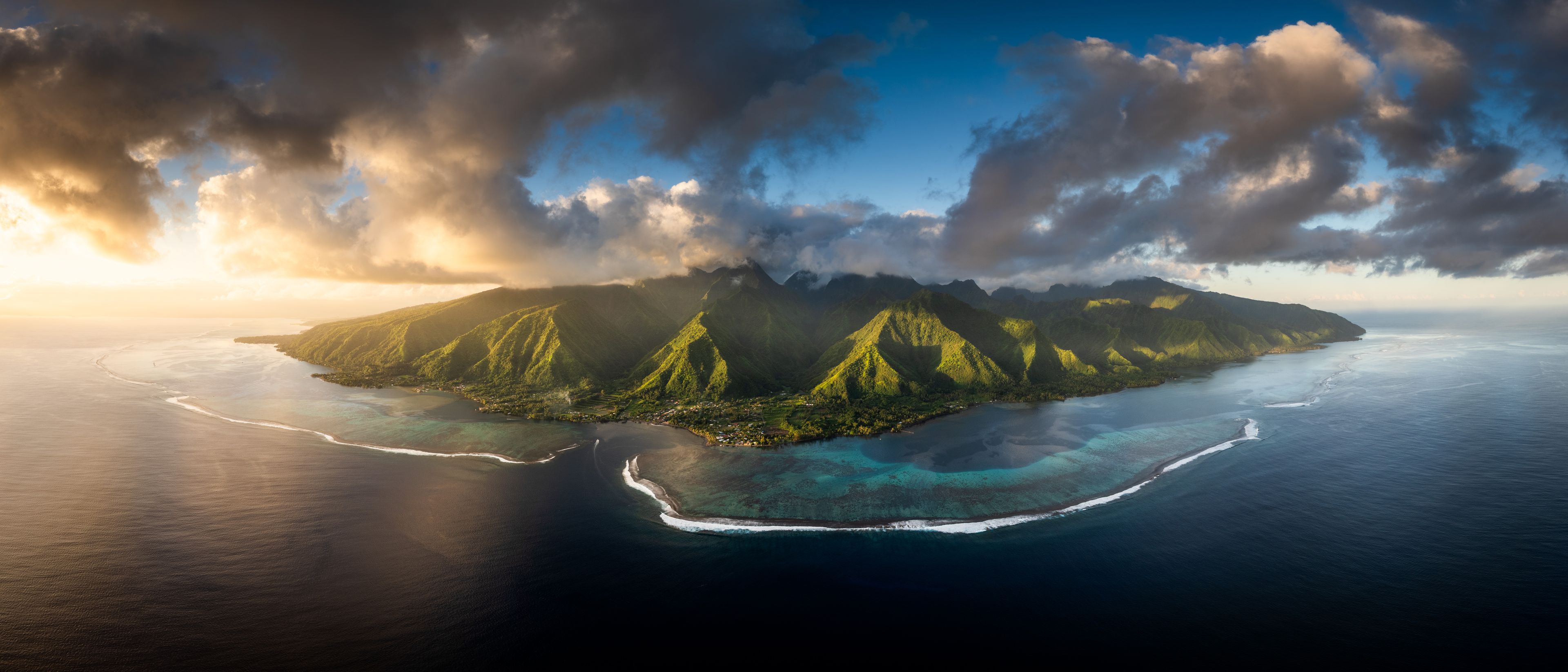 Aerial view of the lush volcanic peaks and turquoise lagoon of Moorea under dramatic sunset clouds Moorea-Maiao, Windward Islands, French Polynesia.