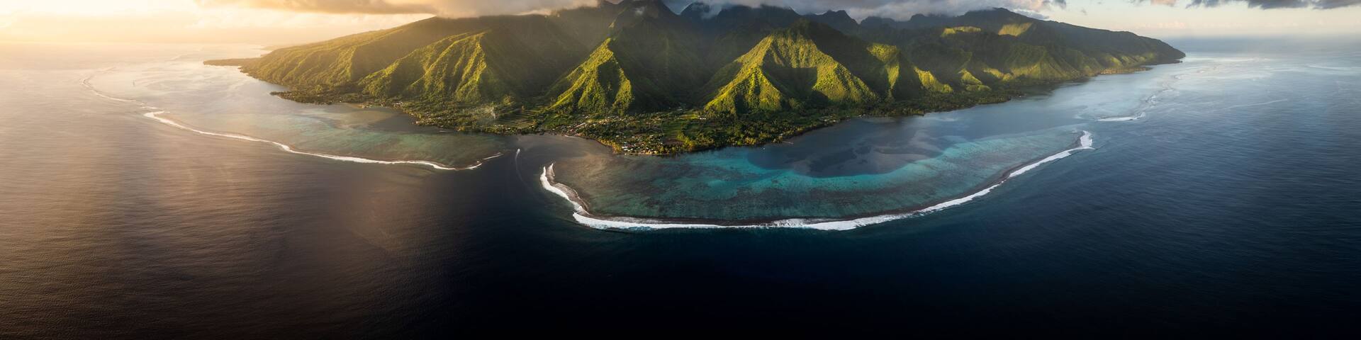 A tropical island with lush green mountains and clear blue waters.