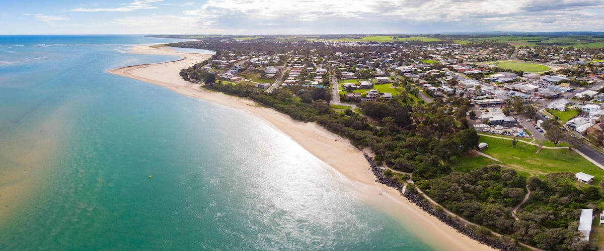 A coastal town with a beach, houses, and greenery.