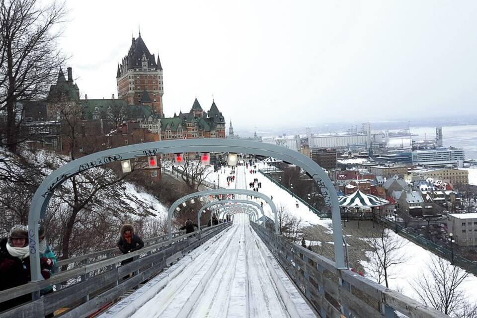 A snow-covered bridge with a view of a historic building in the background.