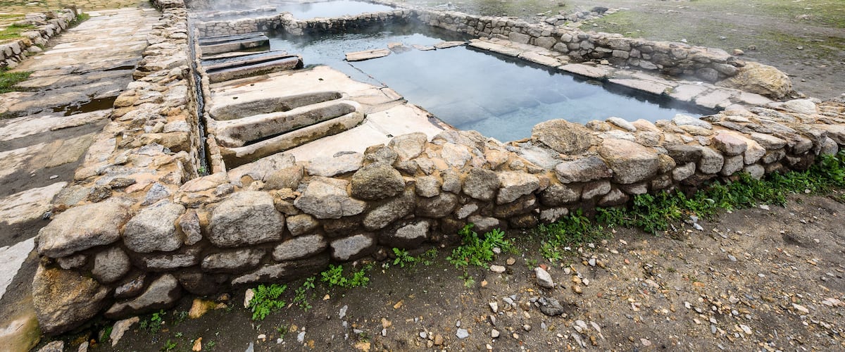 Natural Roman baths outdoors with hot steam and thermal water.
