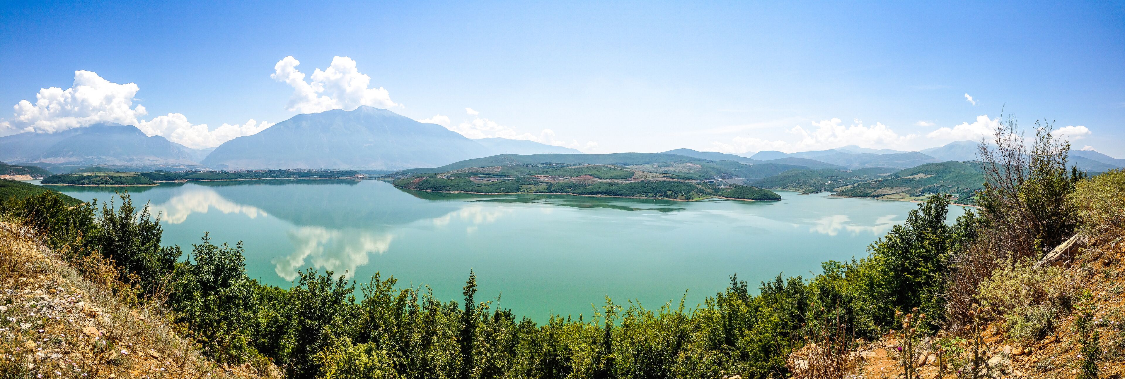 A lake surrounded by mountains and greenery.