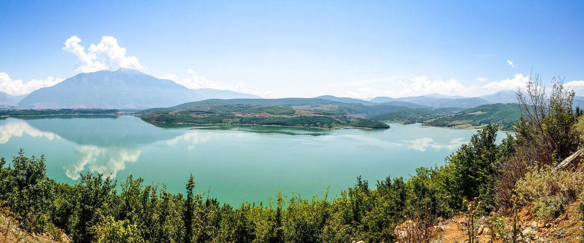A lake surrounded by mountains and greenery.