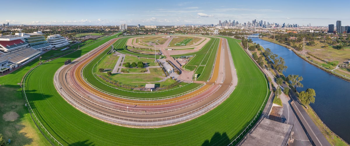 A large racetrack with multiple lanes, surrounded by green fields and a river.