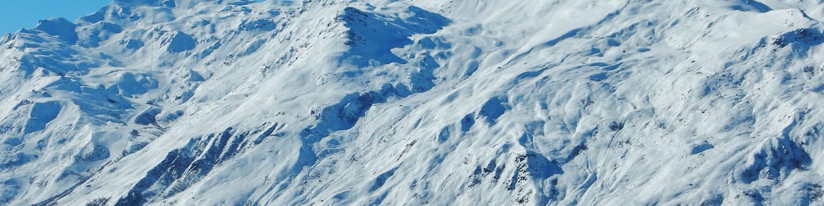 A snow-covered mountain with rugged terrain and sparse vegetation.