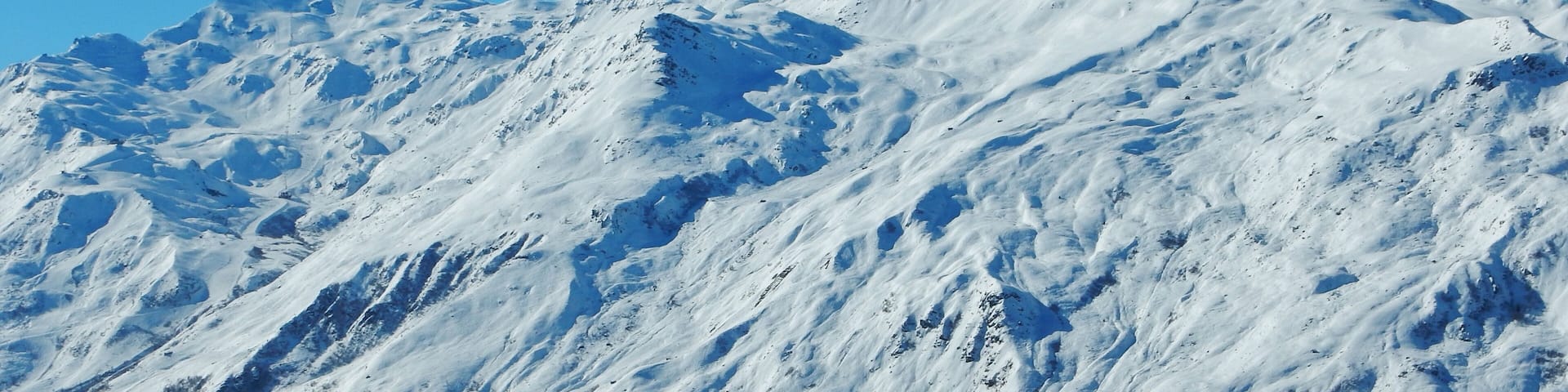 A snow-covered mountain with rugged terrain and sparse vegetation.