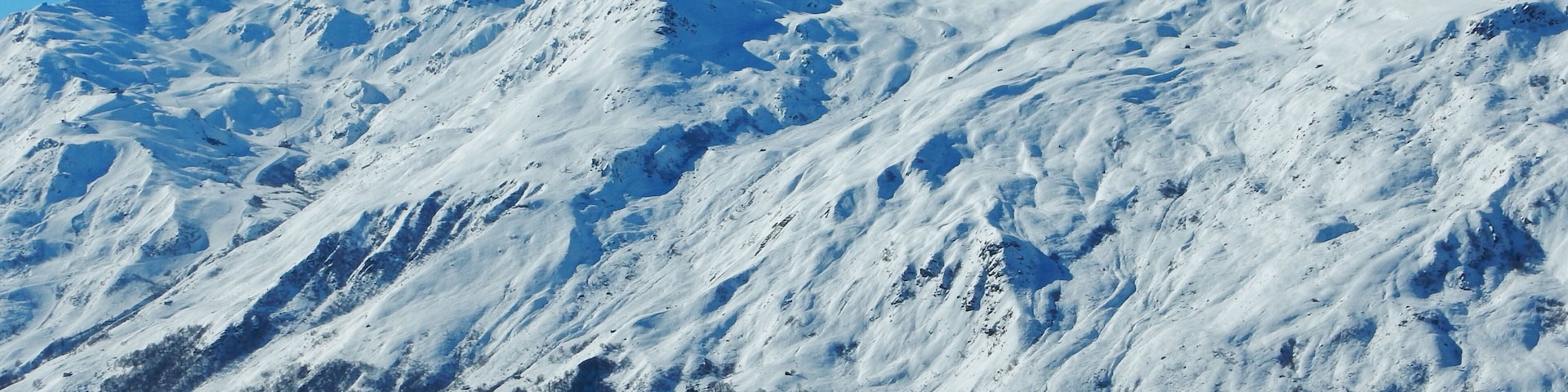 Una montaña nevada con terreno accidentado y vegetación escasa.