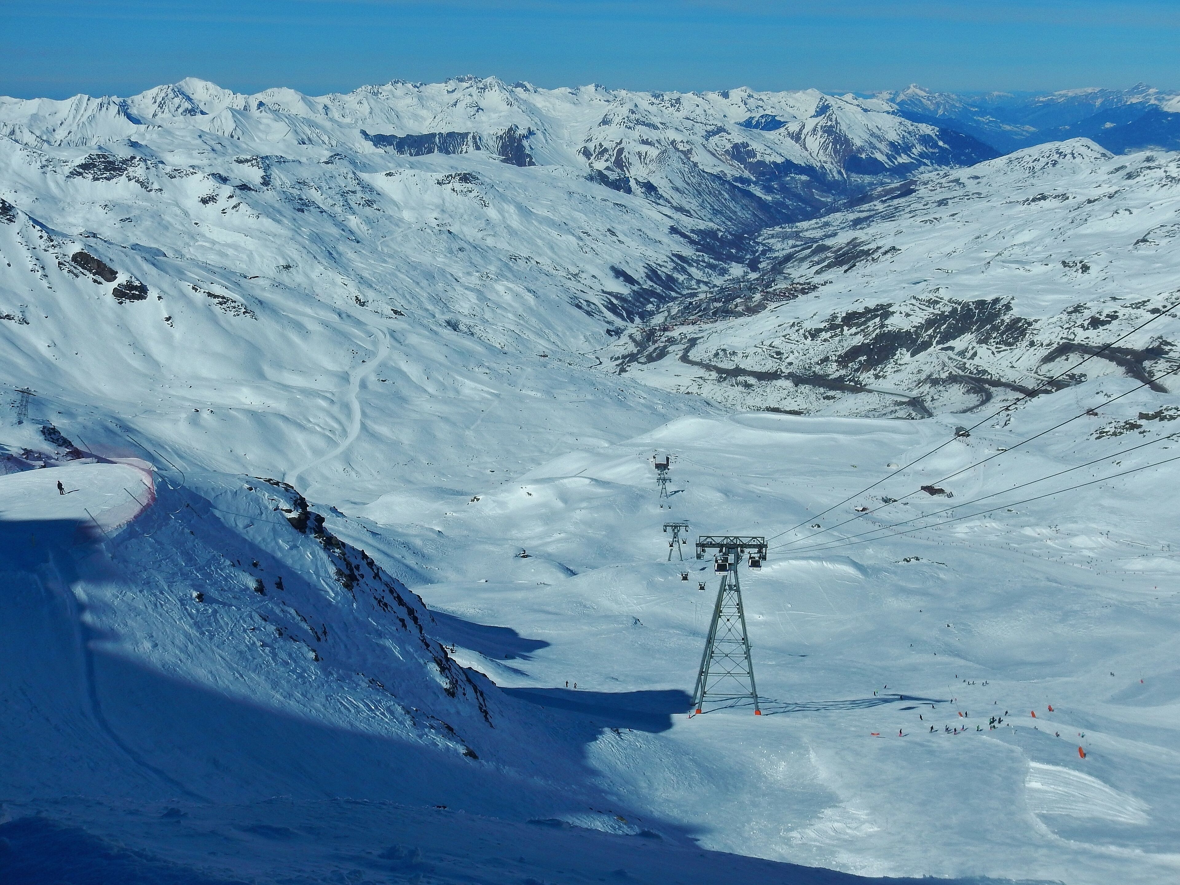 A snowy mountain landscape with ski lifts and skiers.