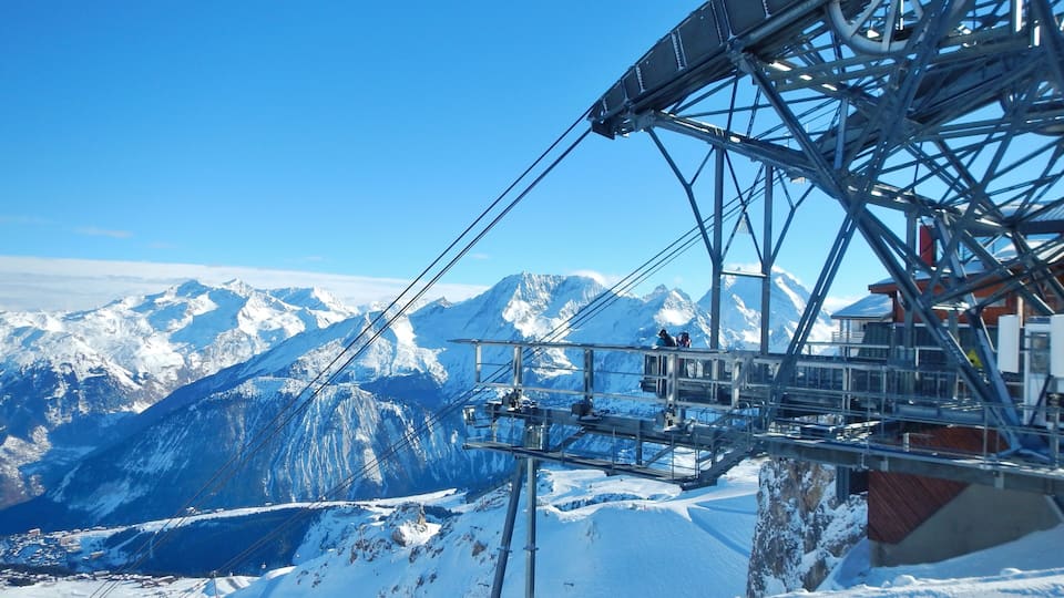 A ski lift with a snowy mountain landscape in the background.