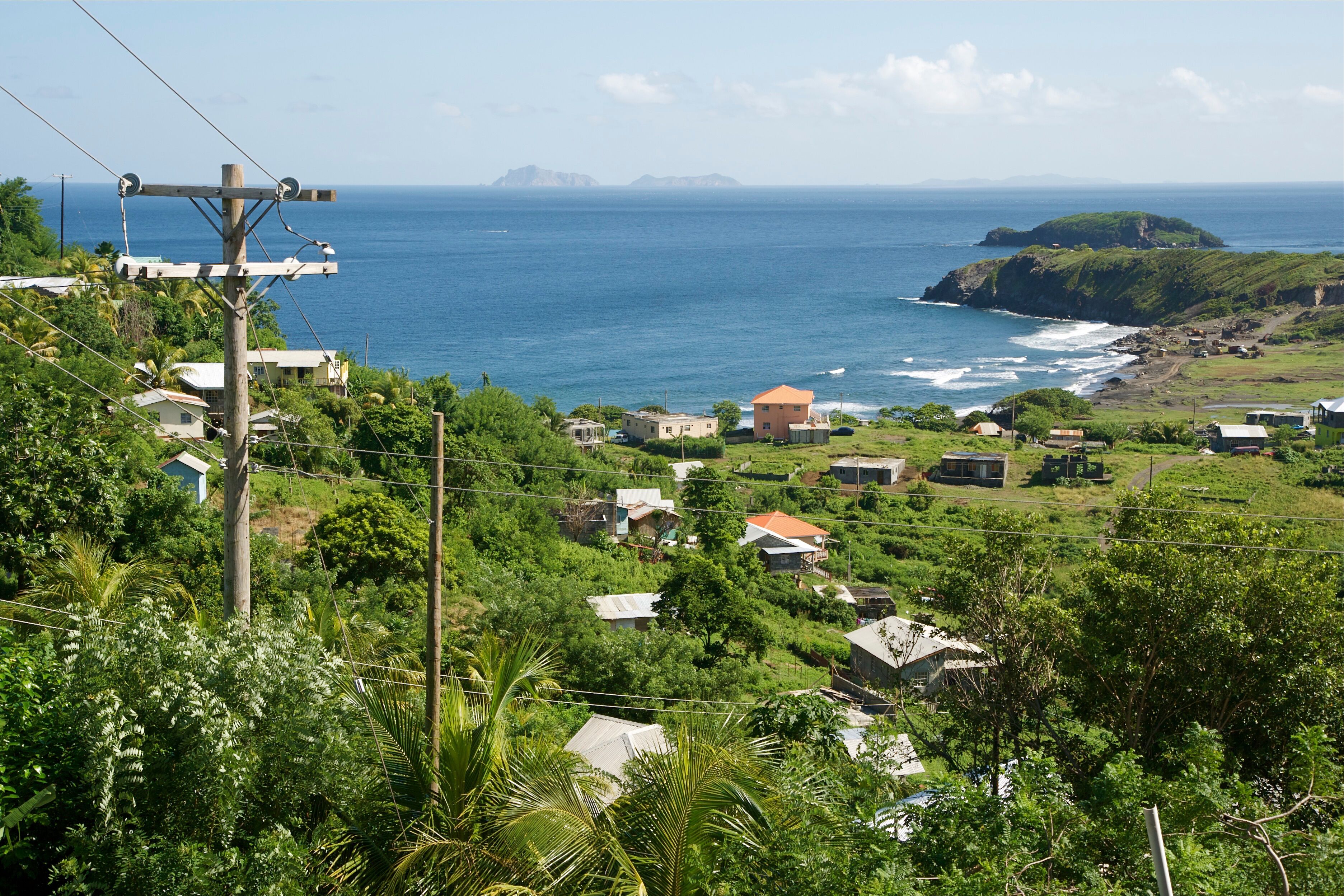 A coastal village with houses, lush greenery, and the ocean.