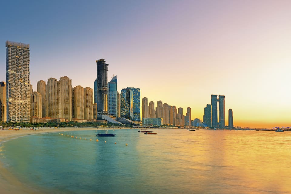 A coastal cityscape with high-rise buildings, a beach, and a Ferris wheel.