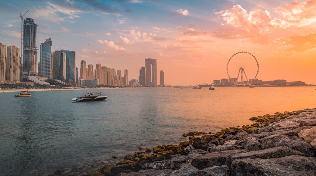 A delightful and colorful sunset over Blue waters Island with the famous Dubai Eye Ferris wheel. Panoramic view of the city in UAE