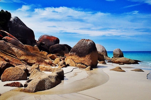 A beach with large rocks and a clear blue sky.