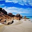 A beach with large rocks and a clear blue sky.