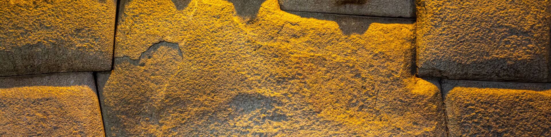 Primer plano de una pared de piedra con textura rugosa y signos de desgaste.