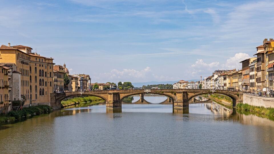 A stone bridge over a river with buildings on either side.