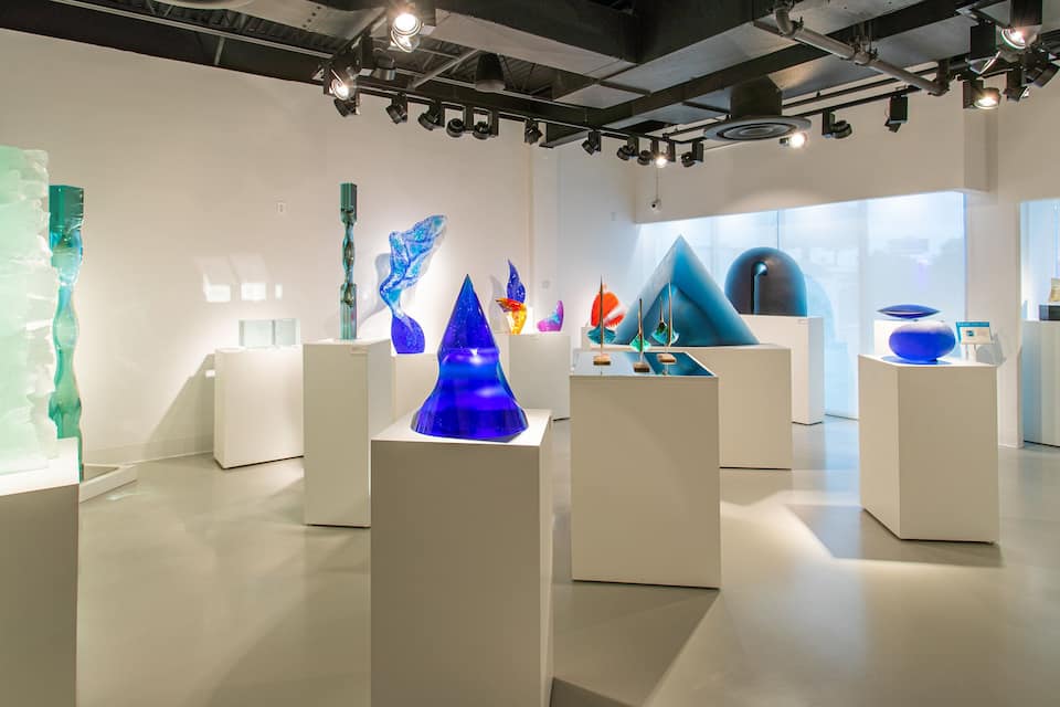 An art gallery with various glass sculptures on display.