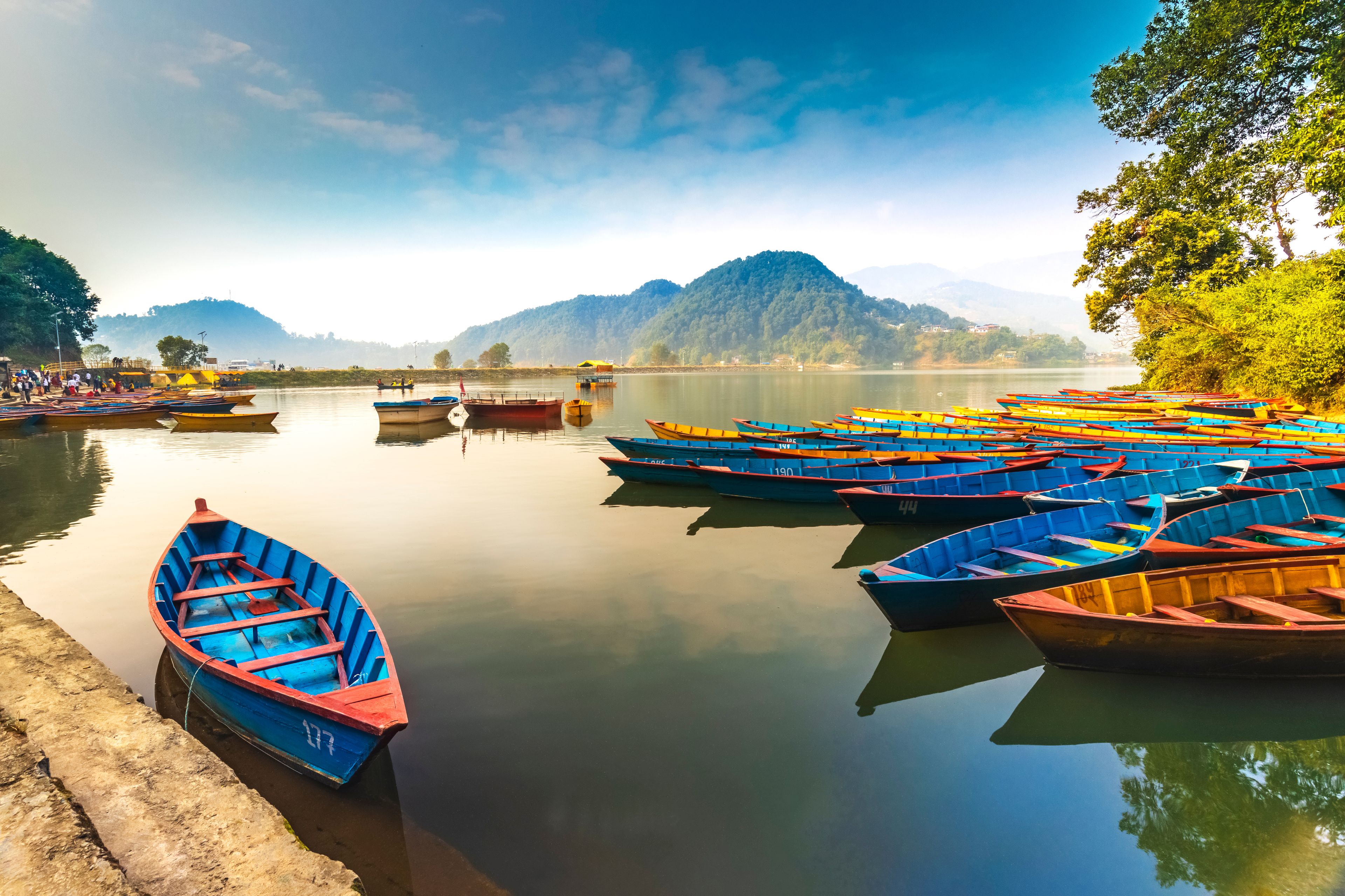 A calm lake with numerous colorful boats docked along the shore.