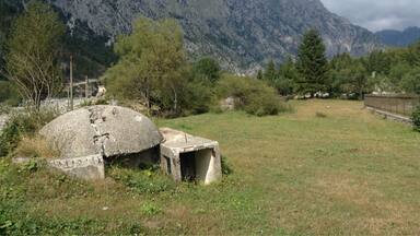 A mountainous landscape with a stone structure and a grassy field.