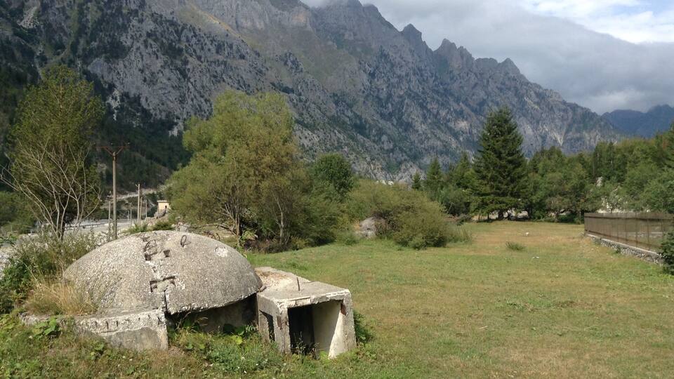 A mountainous landscape with a stone structure and a grassy field.