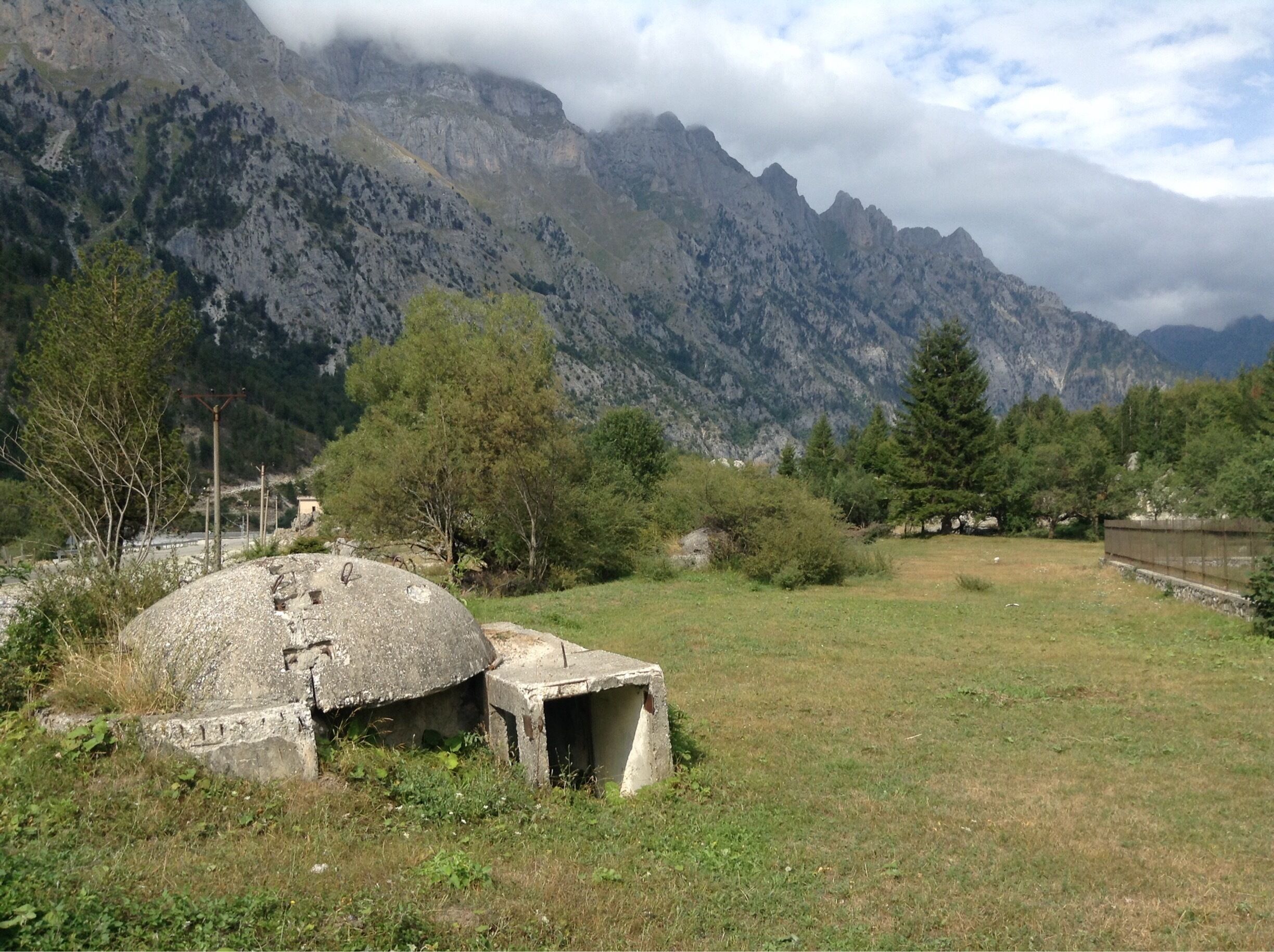A mountainous landscape with a stone structure and a grassy field.