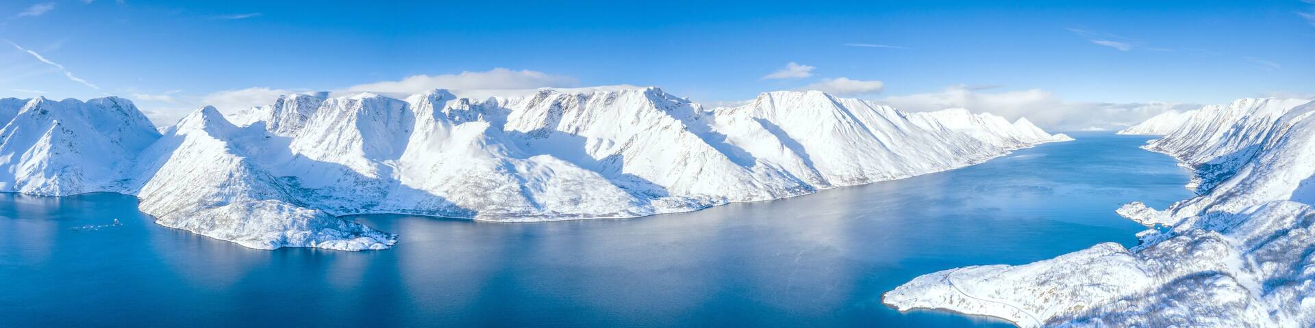 Aerial view of snow capped mountains and fjord during the cold arctic winter, Oksfjord, Troms og Finnmark