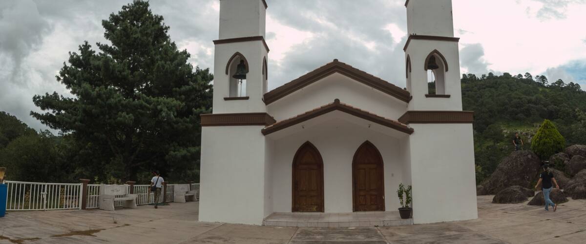 A small white church with two bell towers and a cross on top.