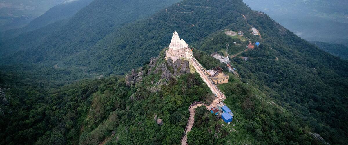A temple on a mountain peak surrounded by dense forest.
