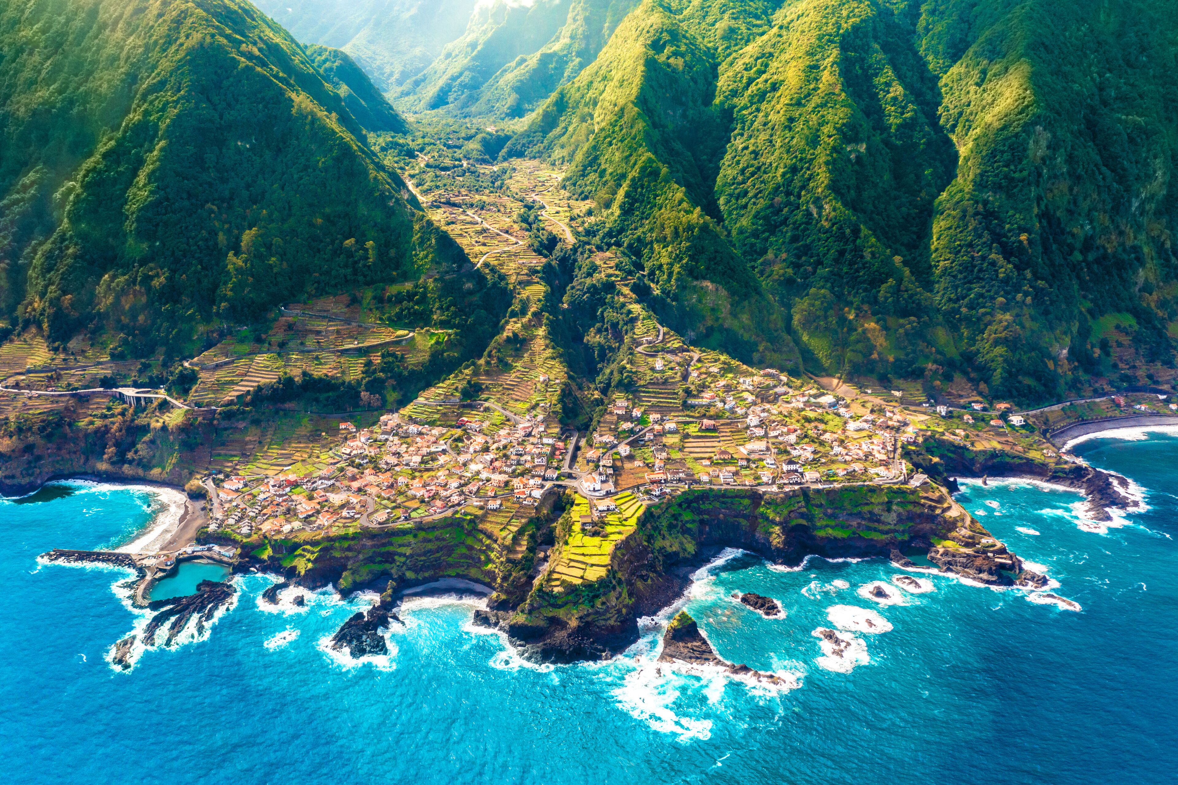 A coastal village nestled between lush green hills and the ocean.