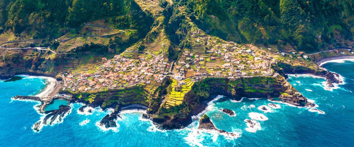 A coastal village nestled between lush green hills and the ocean.