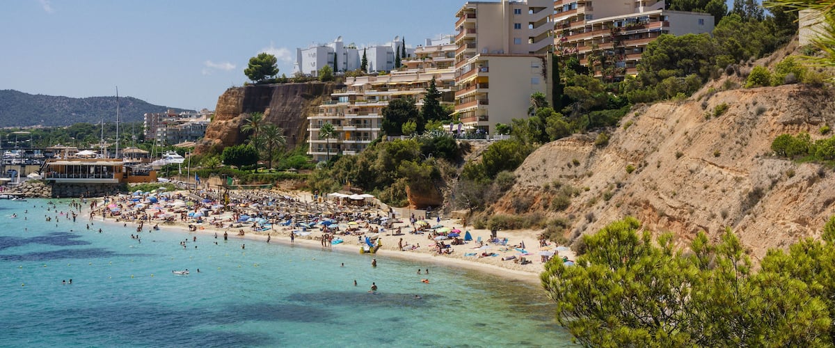 Une ville côtière dotée d’une plage, d’une eau d’un bleu limpide et de bâtiments construits sur une colline.