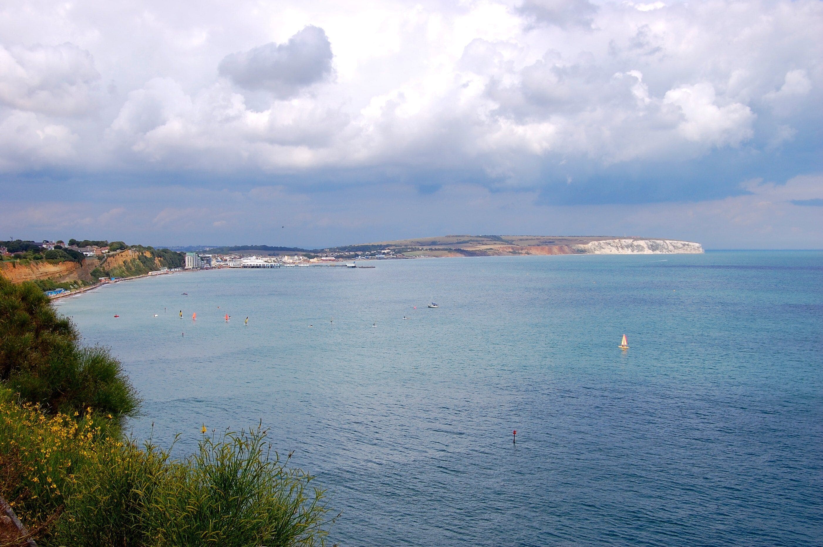 Sandown is a seaside resort town and civil parish[1] on the southeast coast of the Isle of Wight, England, neighbouring the town of Shanklin to the south. Sandown Bay is the name of the bay off the English Channel which both towns share, and it is notable for its long stretch of easily accessible golden sandy beach. It is the site of the lost Sandown Castle. Whilst undergoing construction, this was attacked by a French force which had fought its way over Culver Down from Whitecliff Bay, resulting in the French being repulsed. It was built too far into the sea and constantly suffered erosion, until now reduced to a pile of rocks. Later forts in the town include the Diamond Fort (named after its plan), built inshore to replace the castle and which fought off a minor attack from privateers (probably French) in 1788, and the present "Granite Fort", which is now the zoo. The sweeping esplanade from Devonia Steps to Yaverland and the bandstand were built during the First World War, for the first time stabilising the road to Bembridge. An extension to Brown's Golf Course (and former ice cream factory) was added in 1944 to disguise pumping apparatus for the Pipe Line Under the Ocean (PLUTO) pumping oil to the D-Day beaches, which still stands next to the large Art Deco Grand Hotel. Sandown Bay is often used as a sheltered anchorage, especially for ships requiring salvage which are periodically towed into the bay (such as the Tarpenbeck) and the wreck of a salvage tug can still be seen at low tide under Culver Cliff (the Harry Sharman) which had been assisting the stricken tanker Pacific Glory in the 1970s.