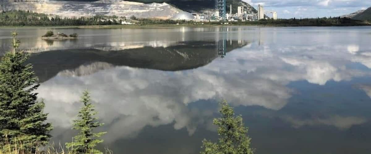 A calm lake with a reflection of mountains and a clear sky.