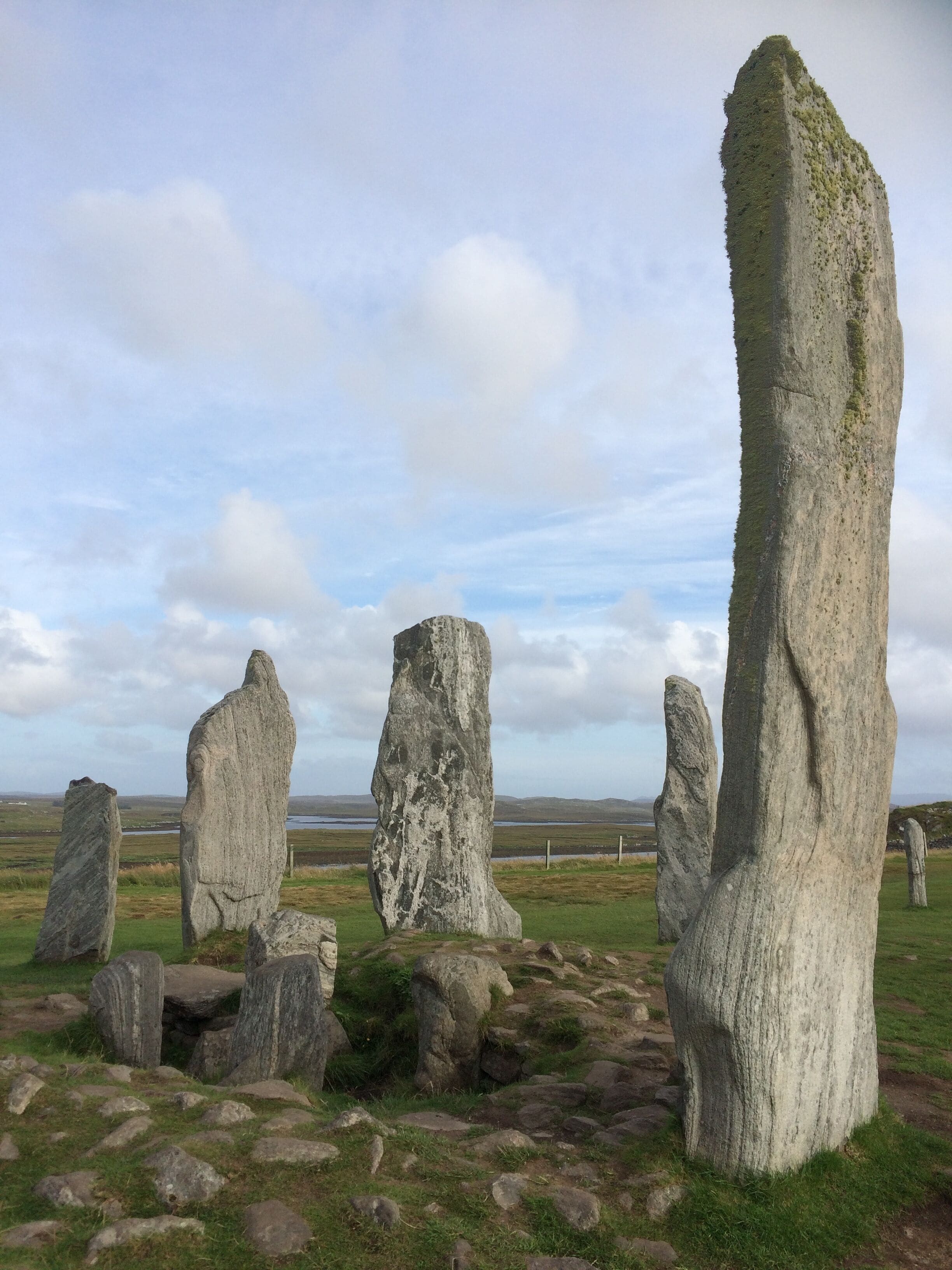 A stone circle with tall standing stones in a grassy field.