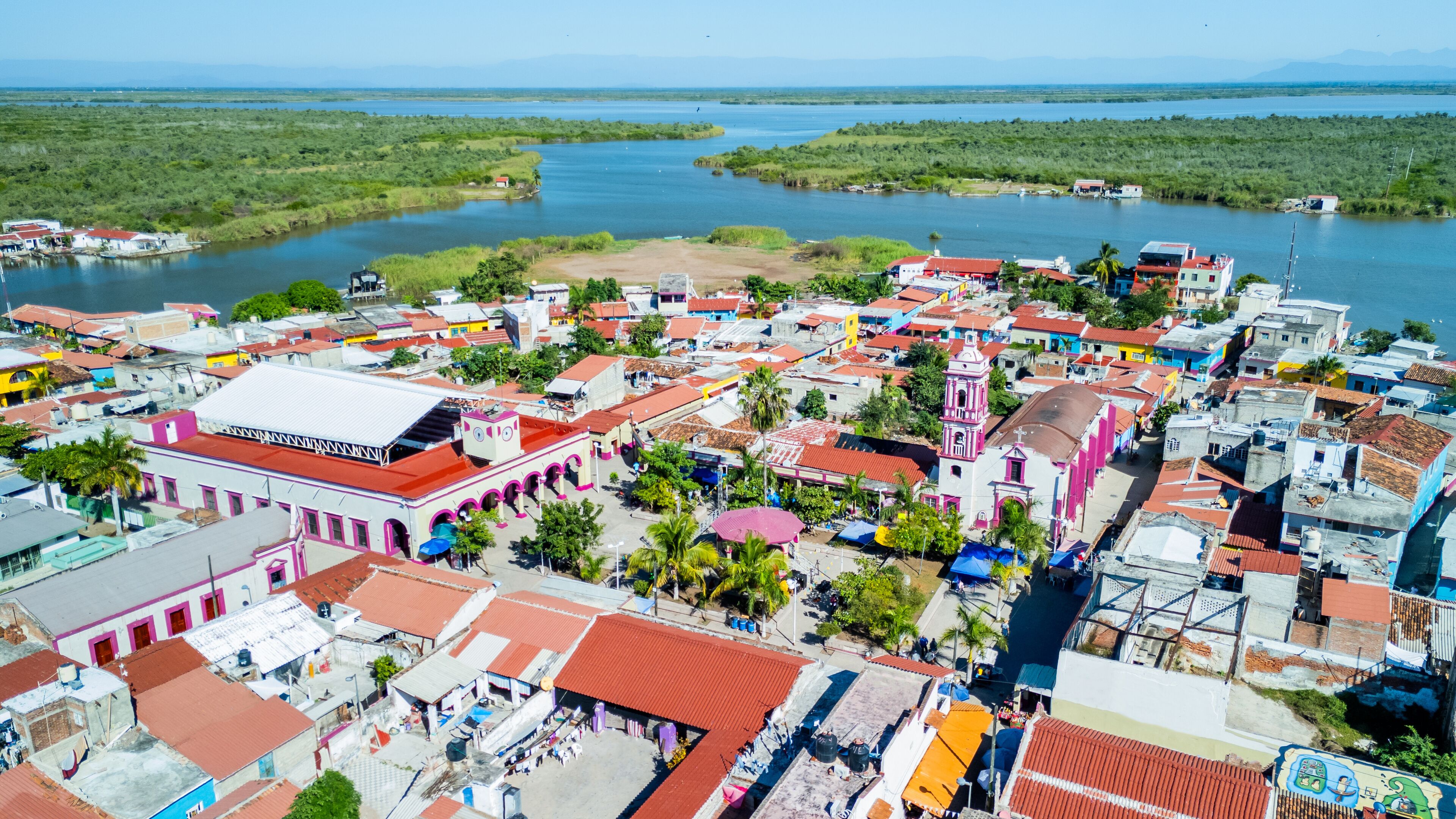 A coastal town with colorful buildings, a river, and a distant mountain range.
