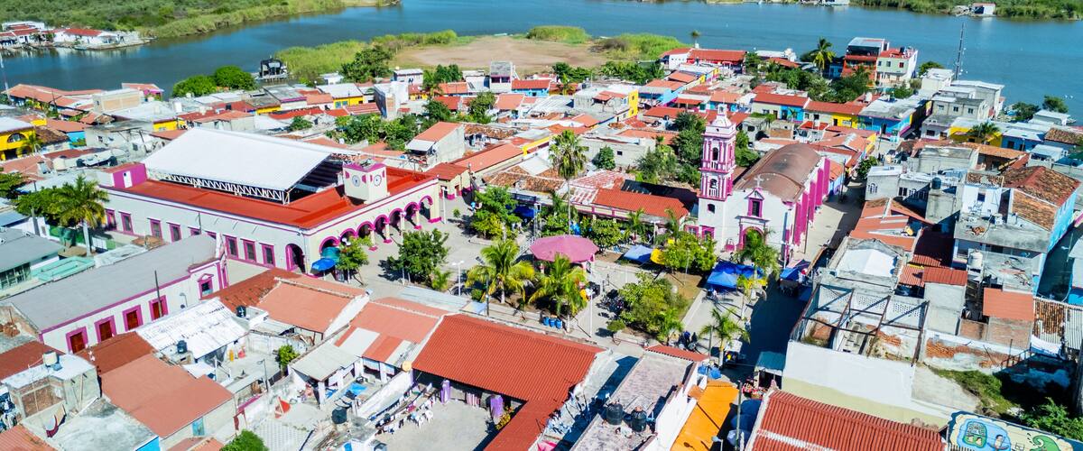 A coastal town with colorful buildings, a river, and a distant mountain range.