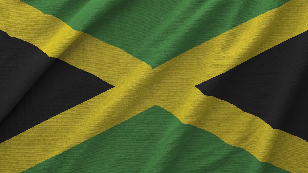 Jamaica flag depicted on folded wavy fabric of old cloth close up