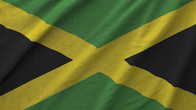 Jamaica flag depicted on folded wavy fabric of old cloth close up