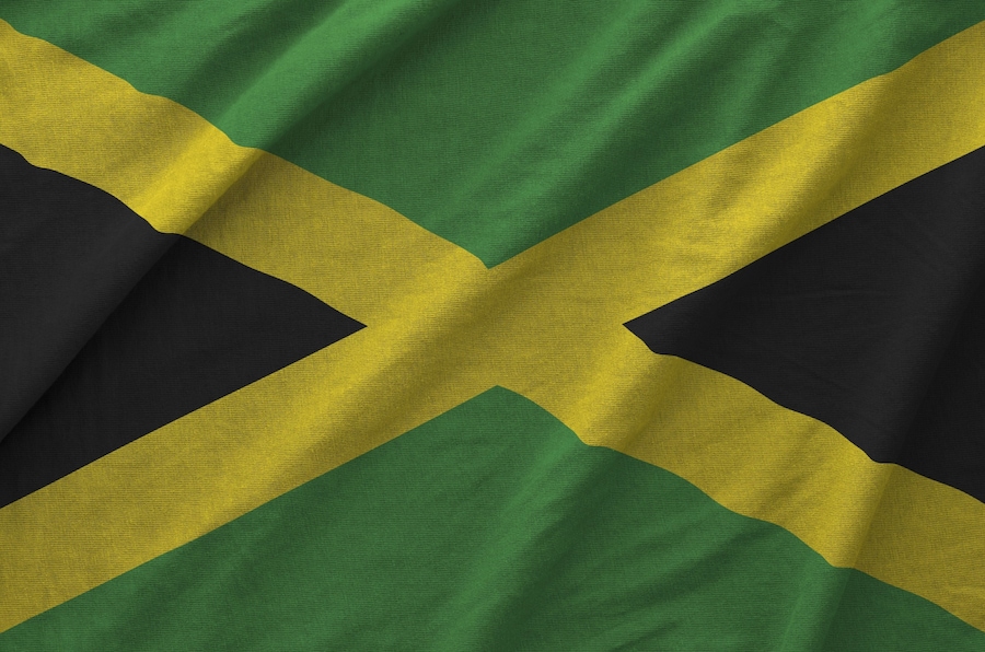 Jamaica flag depicted on folded wavy fabric of old cloth close up