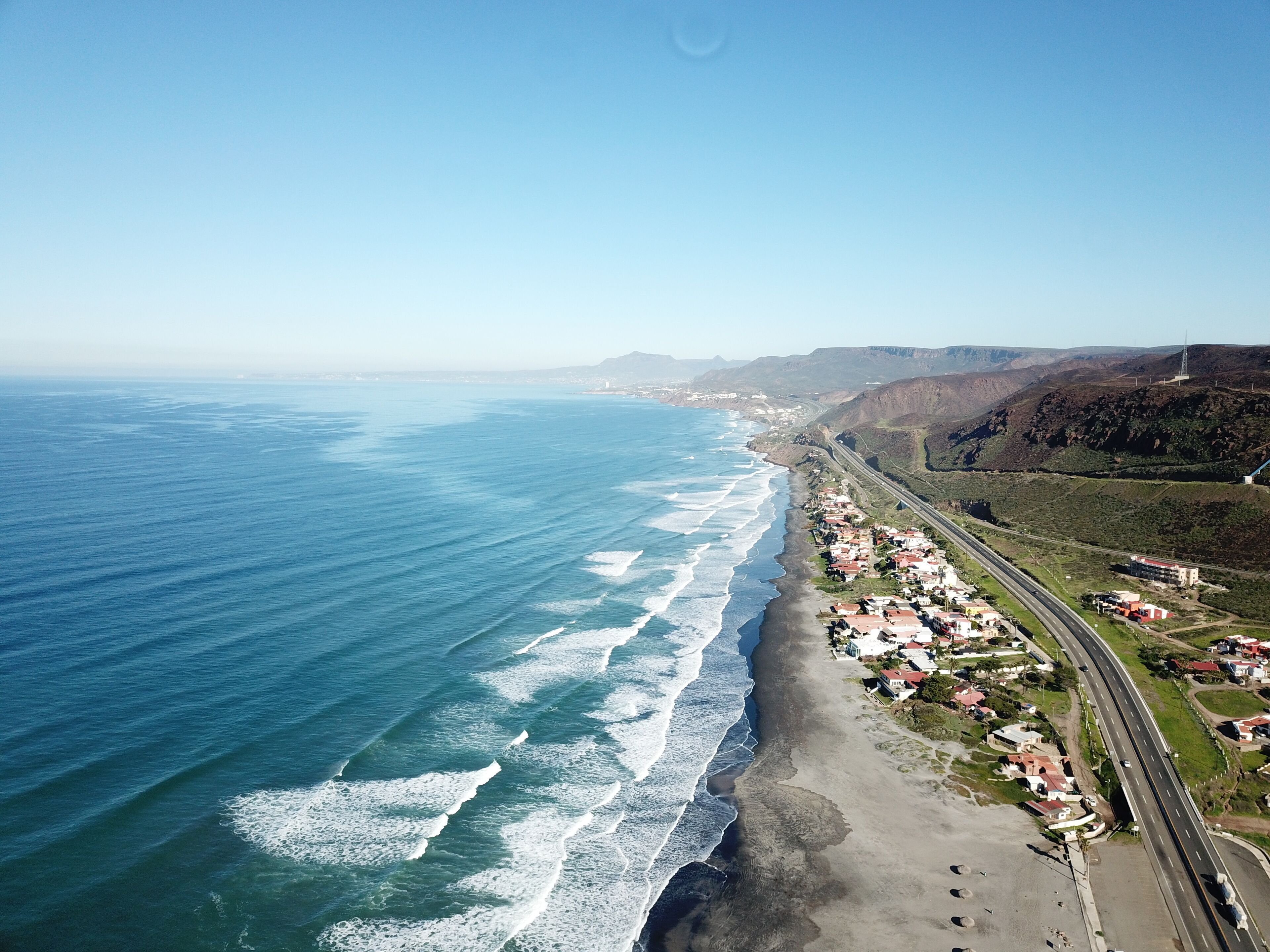 A coastal town with a beach, ocean, and a highway.