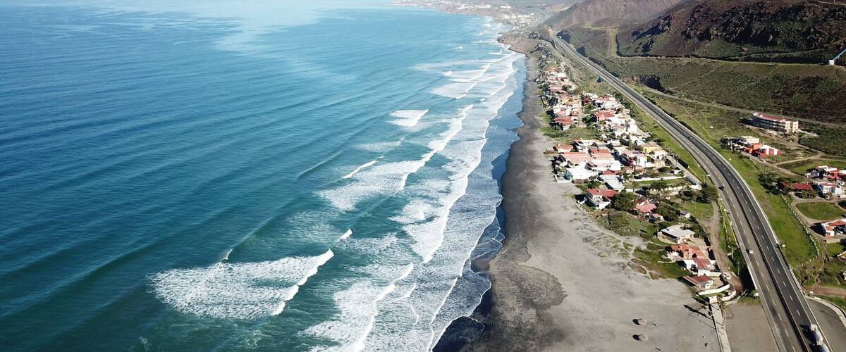 A coastal town with a beach, ocean, and a highway.