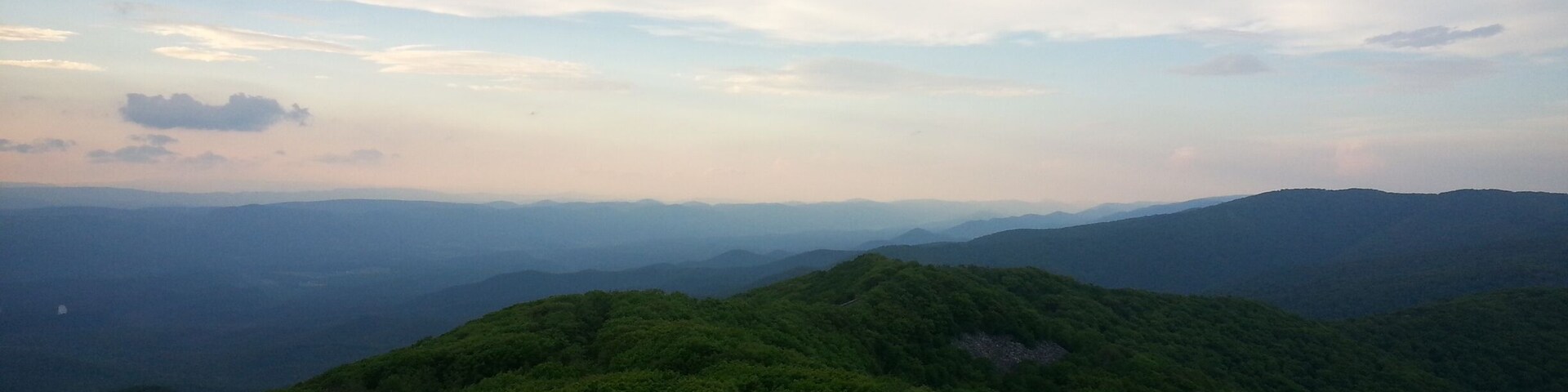 A mountainous landscape with dense green forests and a clear sky.