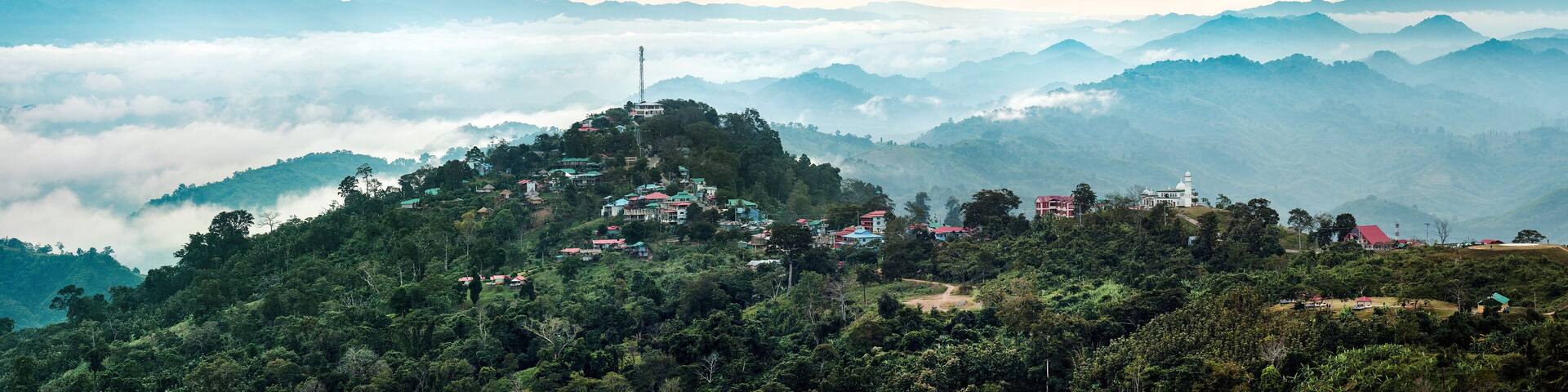 Sajek, Bangladesh - 04 December 2023: View of the undulating hills and valleys shrouded in a soft, ethereal mist, dotted with clusters of houses and structures.