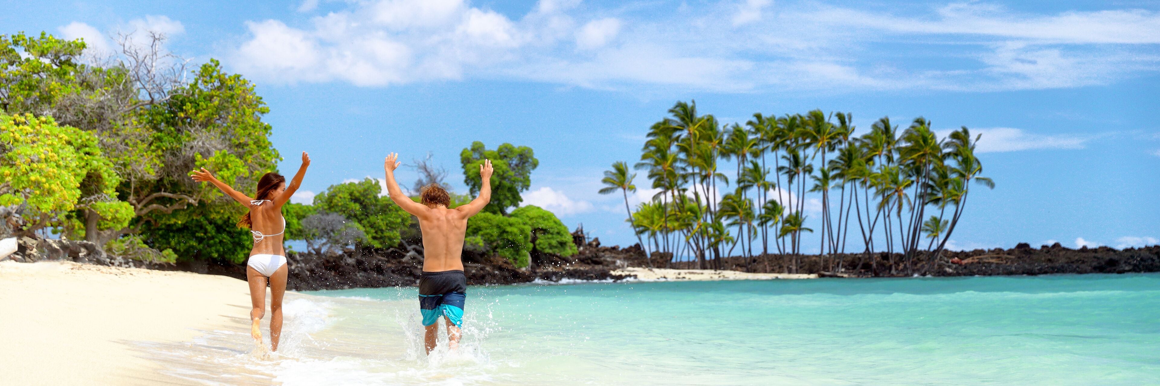 Summer fun beach couple running of joy banner with arms up in success on travel holidays. Happy people on tropical landscape background panoramic copy space.