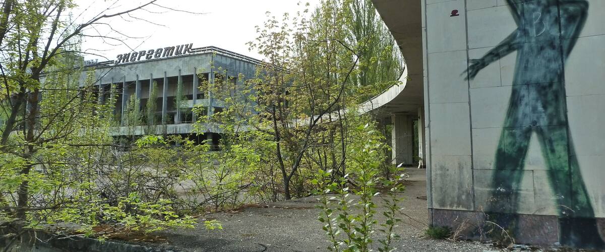 A building with graffiti, trees, and a concrete structure.