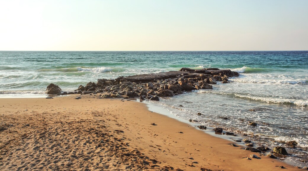 Empty beach with footsteps, some rocks in sea, in evening few moments before sunset. Lapta, Northern Cyprus