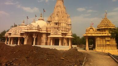A temple with intricate carvings and multiple domes, surrounded by a construction site.