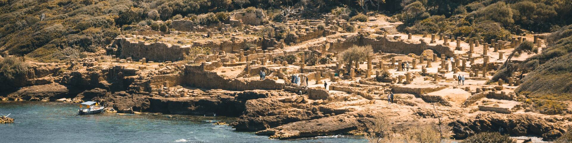 Wide angle panorama of the ruins of the Roman Archeological Park of Tipaza, Tipasa, Algeria. Tourists on the site.