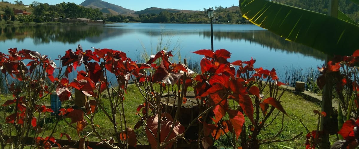 A lake with red foliage in the foreground and mountains in the background.