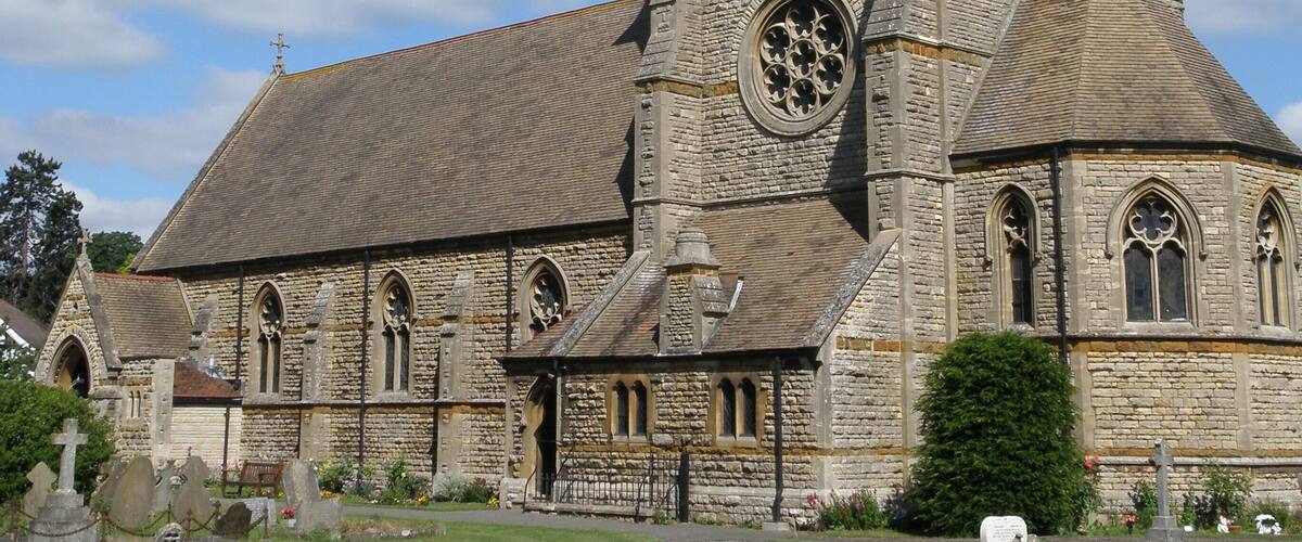 A stone church with a tall tower and a large circular window.